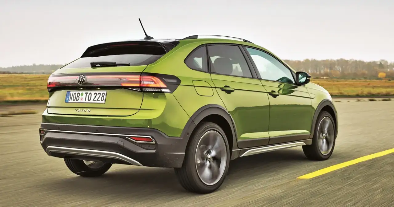 Zielony Volkswagen Taigo pędzi po drodze, ukazując swoje sportowe linie i nowoczesny design.