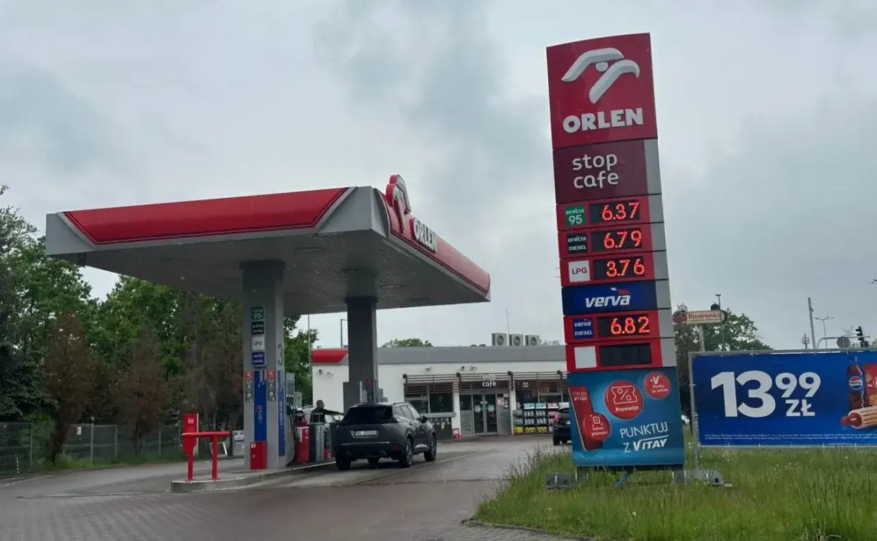 Stacja Orlen z widoczną ceną ropy i innych paliw. Obok billboard z promocją.
