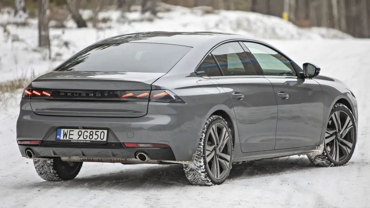Szary Peugeot 508 na śniegu, z widocznymi zimowymi oponami gotowymi na trudne warunki.