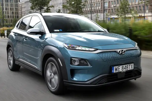 Niebieski Hyundai Kona na drodze, z widocznymi detalami, które mogą być brane pod uwagę jako **hyundai kona wady**, np. nietypowy design przedniego grilla.