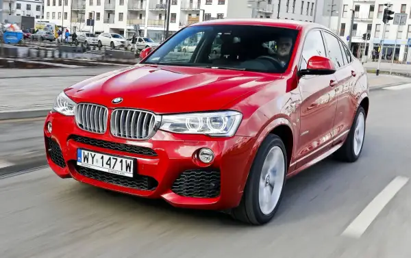Czerwone BMW X4 w ruchu miejskim. Wady tego modelu to m.in. ograniczona widoczność z tyłu i wysoka cena.