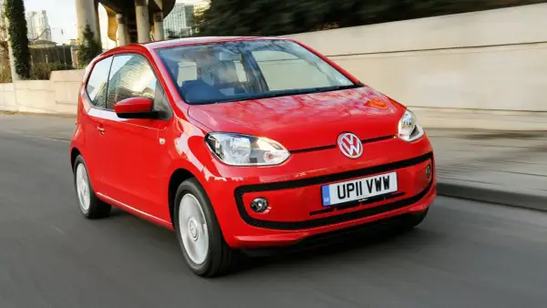 Czerwony Volkswagen Up w ruchu miejskim. Choć jego kompaktowe wymiary to zaleta, warto rozważyć potencjalne volkswagen up wady, jak ograniczona przestrzeń.