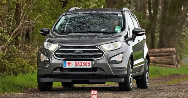 Szary Ford Ecosport na leśnej drodze. Kierowca w okularach za kierownicą.