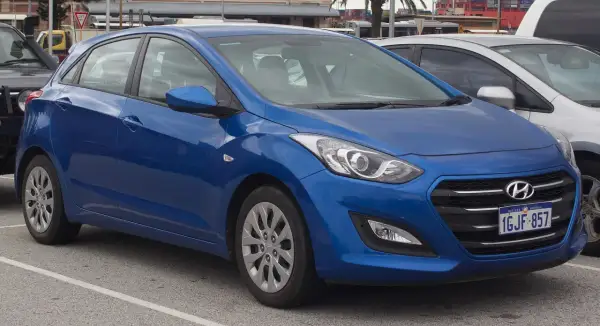Niebieski Hyundai i30 na parkingu. Widoczne felgi i opony, które sugerują standardowy rozmiar dla tego modelu.