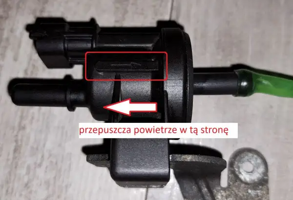 Zawór podciśnienia, potencjalna przyczyna DTC P0172 w Volkswagen. Strzałka wskazuje kierunek przepływu powietrza.