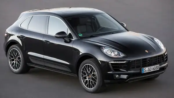 Czarny Porsche Macan na ciemnym tle. Choć piękny, warto znać jego potencjalne wady przed zakupem.
