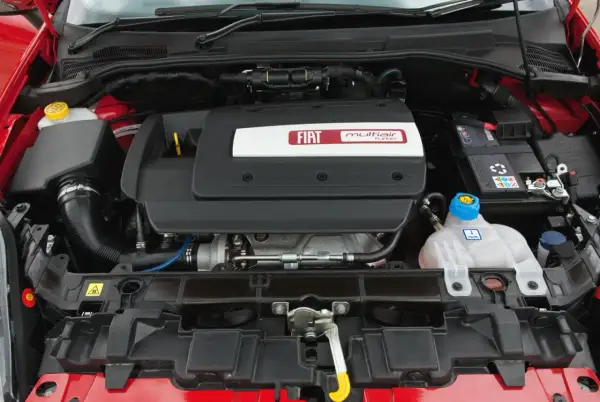 Silnik MultiAir Turbo w czerwonym Fiat Punto 2009. Widoczny akumulator, płyn chłodniczy i elementy układu dolotowego.