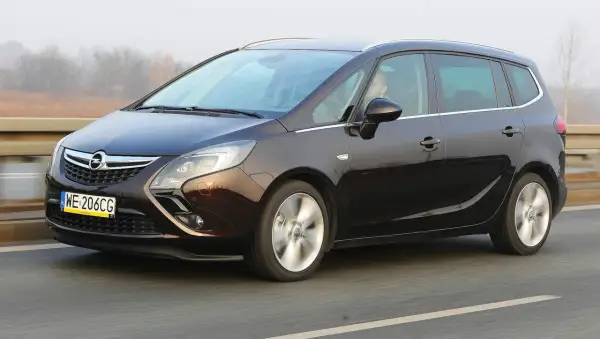 Ciemnobrązowy Opel Zafira Tourer 1.4 Turbo na drodze. Kierowca za kierownicą.