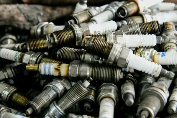 Stos zużytych świec zapłonowych, niektóre z oznaczeniem p0302, gotowe do recyklingu.