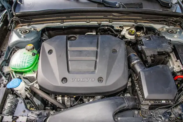 Silnik Volvo T3 z widocznym zielonym płynem w zbiorniczku i czarną osłoną z logo.
