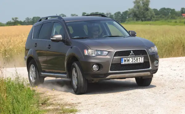 Brązowy Mitsubishi Outlander 2008 na drodze polnej, w tle pole zboża.