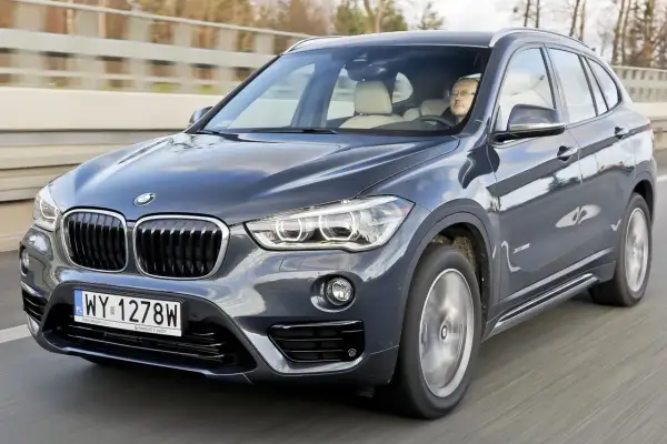 Ciemnoszary BMW X1 2020 na drodze, z kierowcą za kierownicą.