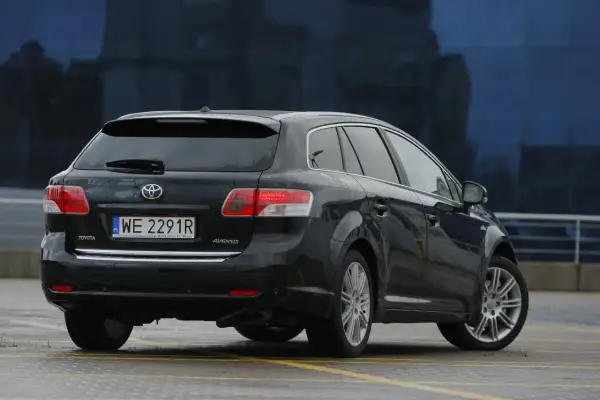 Czarna Toyota Avensis T27 kombi, gotowa na wymianę żarówki w tylnym świetle.